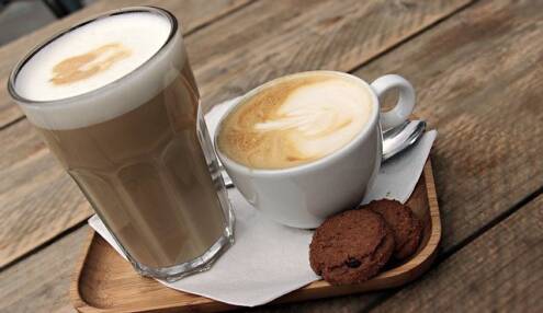 What is a cappuccino, caffe latte next to a cup of cappuccino