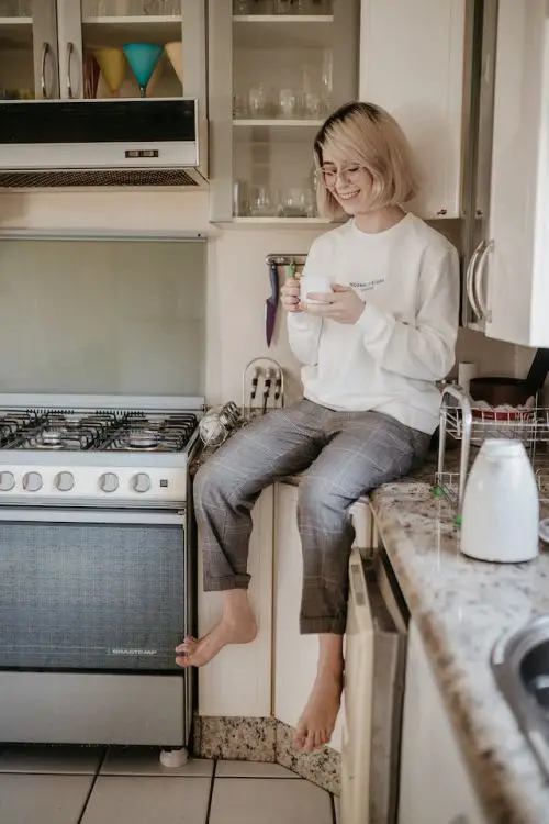 How do They Make Decaf Coffee, a woman enjoying a cup of coffee on her kitchet countertop